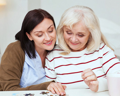 a caregiver and a senior woman doing a puzzle