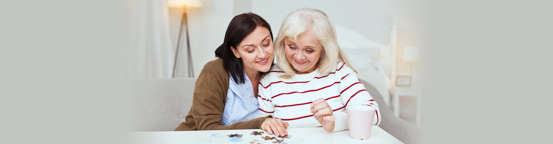 a caregiver and a senior woman doing a puzzle